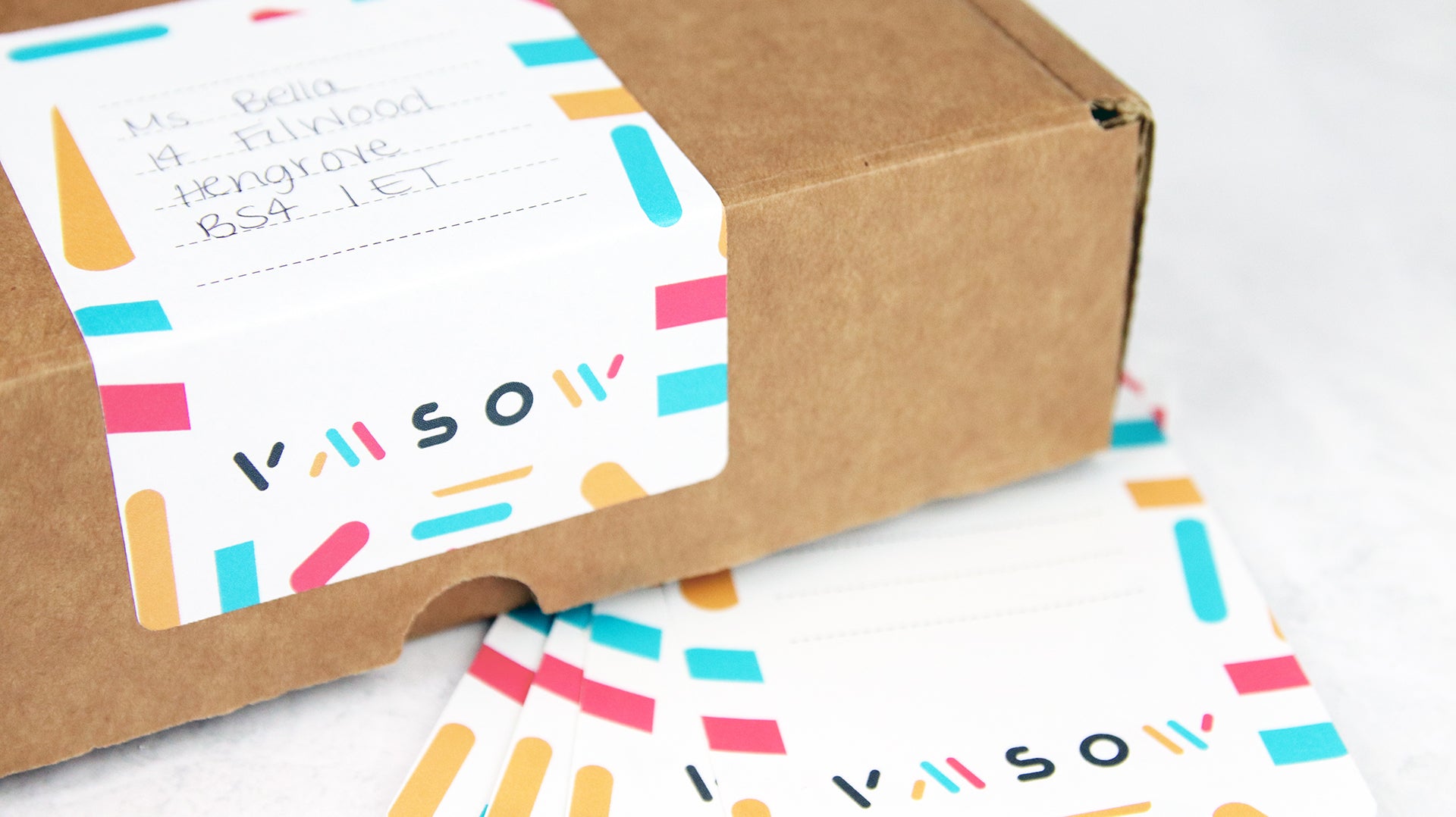 Biodegradable paper sheet labels with rounded corners applied to a cardboard box used as an address label