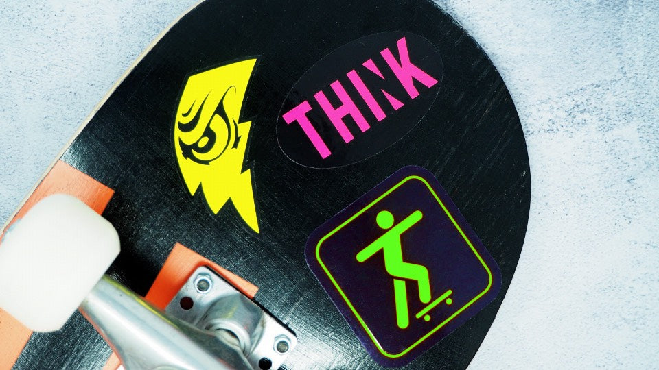 Various fluorescent coloured stickers applied to the underside of a skateboard