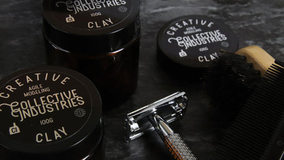 Circle mirror silver labels applied to black tins containing hair care next to a razor and a brush