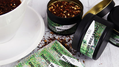 Die cut glitter labels applied to black tea tins next to a white mug