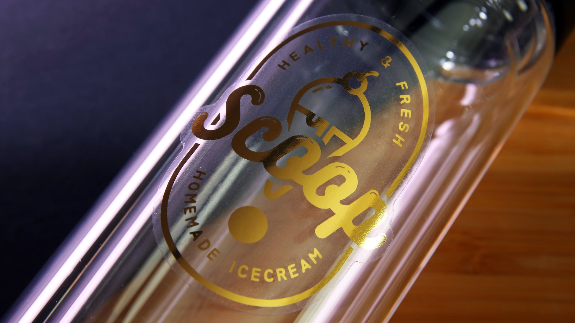 Die cut eco-friendly gold foil sticker with ice cream logo applied to a clear water bottle