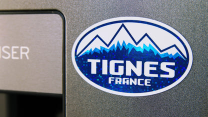 Oval Tignes France design printed on a glittery magnet attached to a silver metal fridge