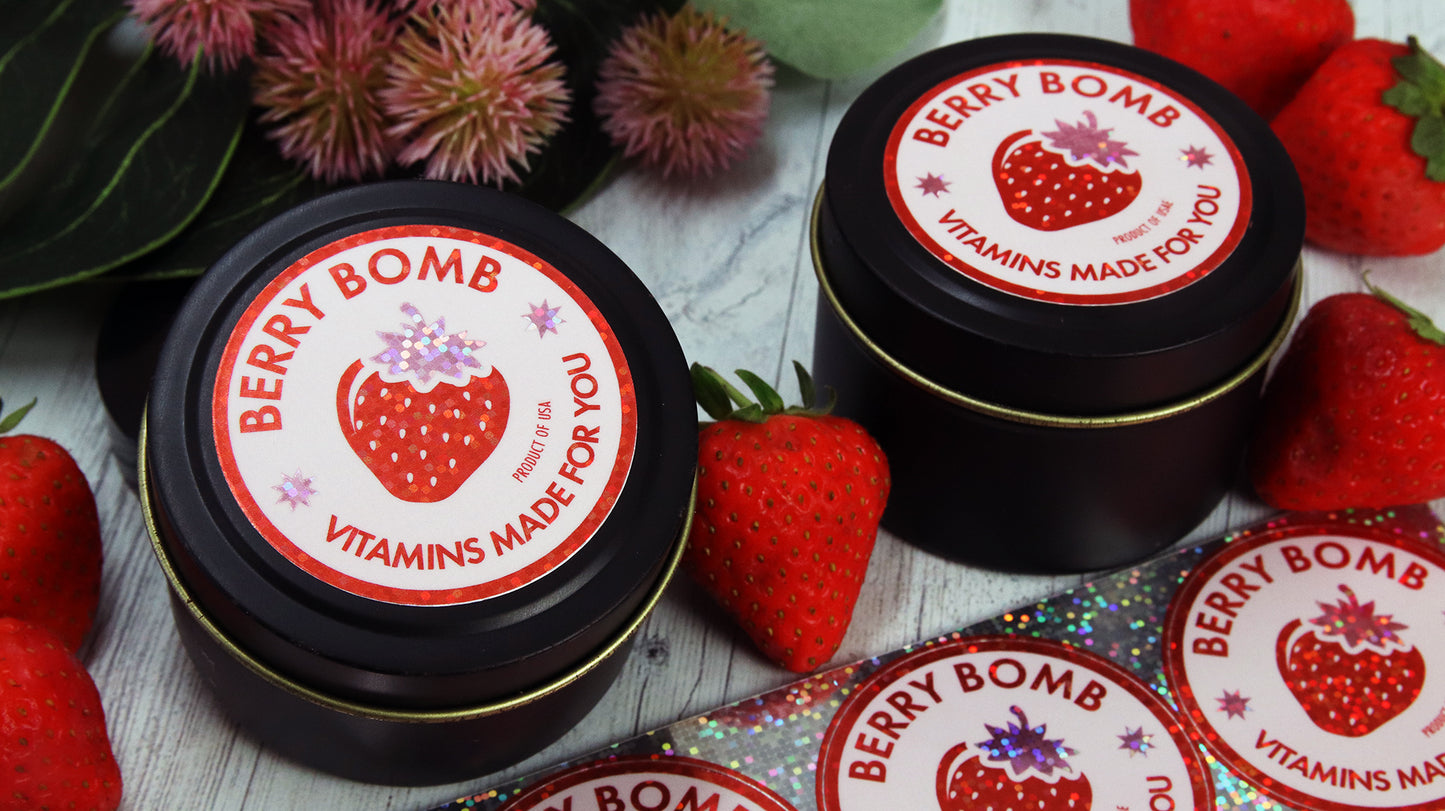 Circle glitter branding labels applied to black tins and a cardboard box containing a custom made vitamin mix next to glitter sticker sheets
