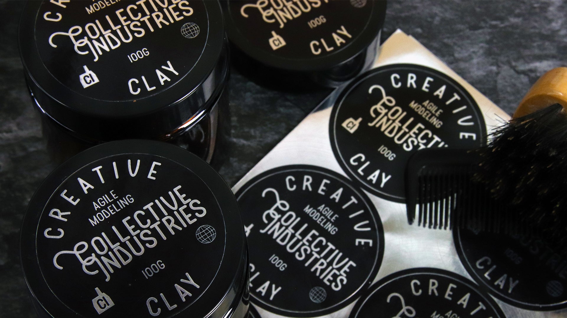 Circle mirror silver branding labels applied to black tins containing hair care next to a sheet