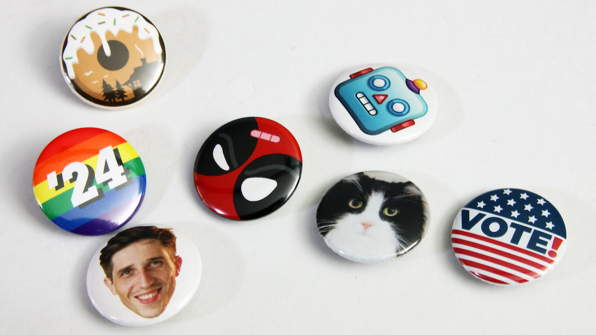 Custom standard button badges on white fabric with a variety of custom designs
