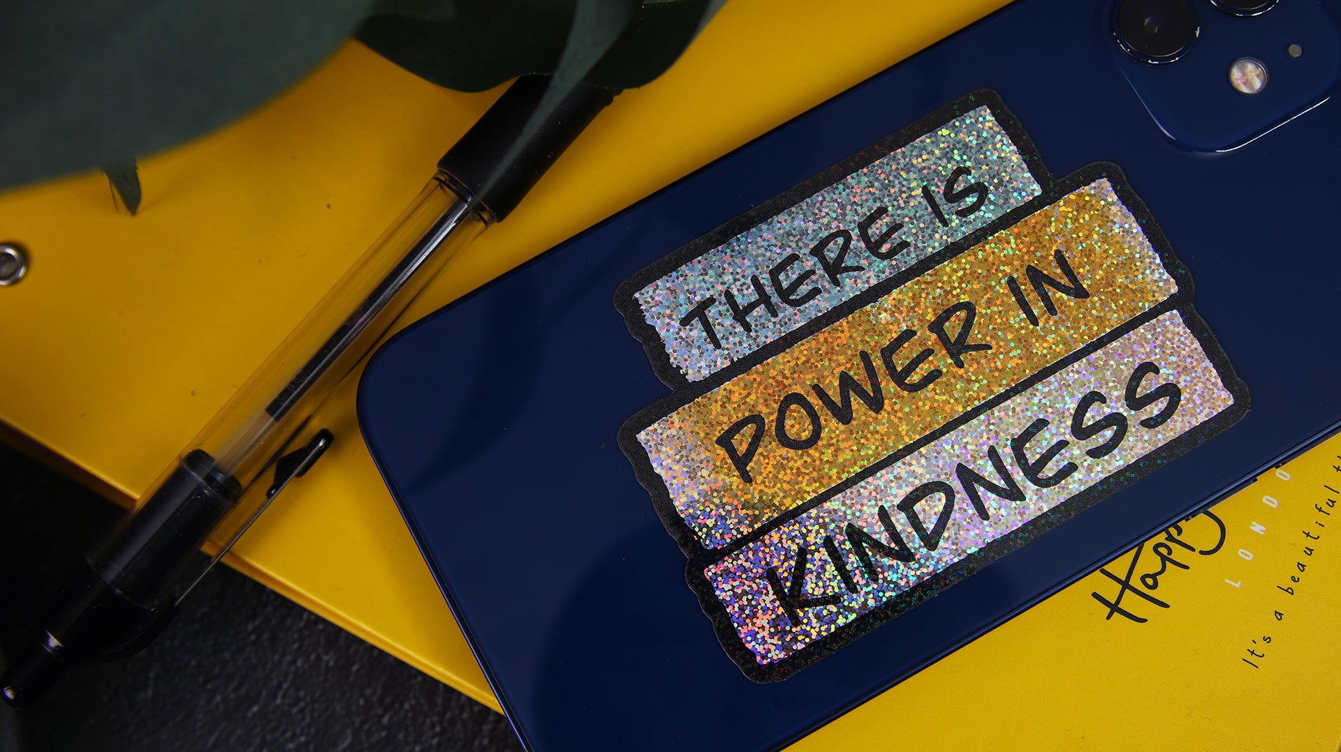 Die cut eco-friendly glitter sticker with there is power in kindness design applied to an iPhone