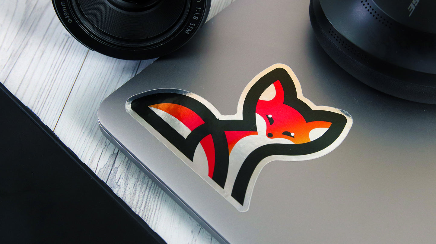 Die-cut mirror-silver label with fox logo design applied to a silver laptop