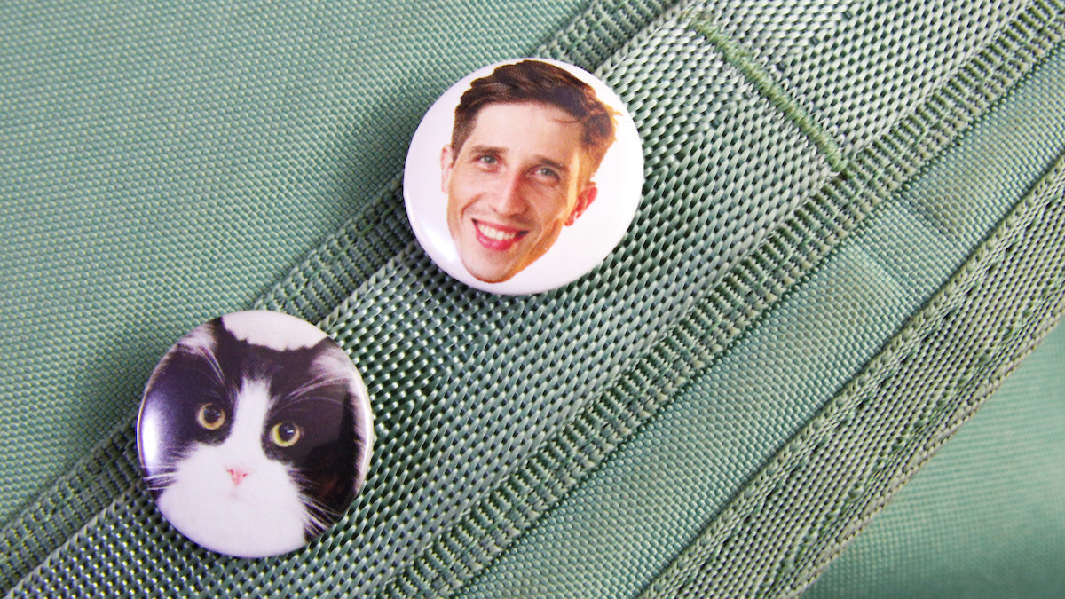 Faces printed on a 1 inch (25mm) button badges pinned to a bag