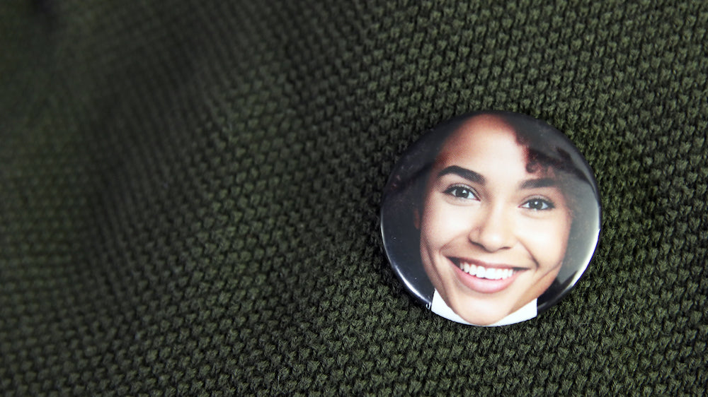 Happy smiley photo of a face printed on a button badge pinned to clothes