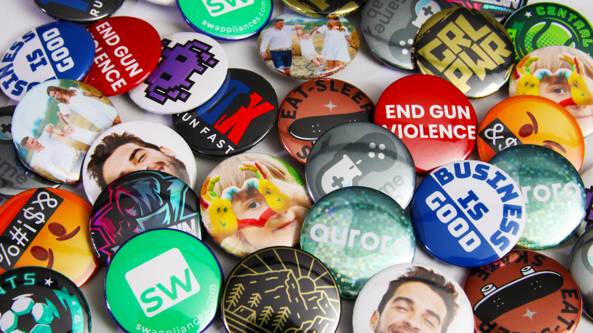 Loads of 32mm (1.25-inch) custom printed buttons and badges scattered on a table