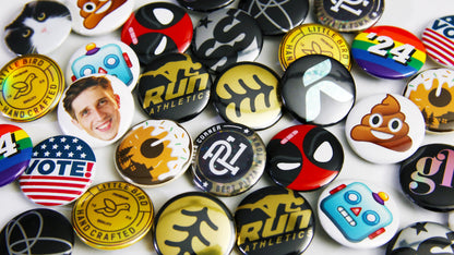Loads of small 25mm (1-inch) custom printed buttons and badges scattered on a table