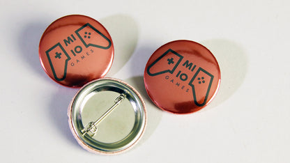 MI IO Games custom metallic silver design on various button badges