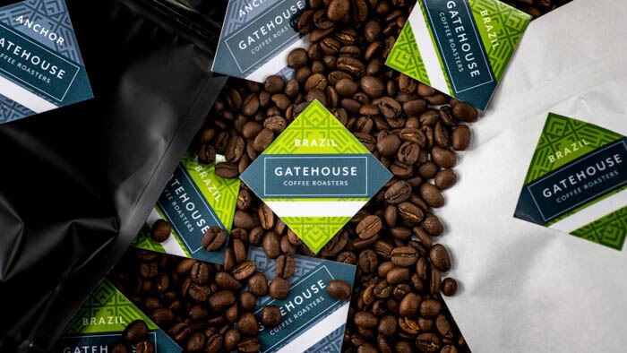 Square white vinyl labels with Gatehouse coffee logo on a bed of coffee beans