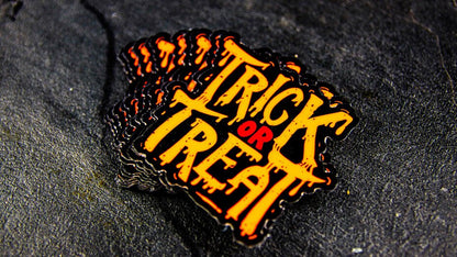 Stack of die-cut fluorescent orange labels with trick or treat design on a table