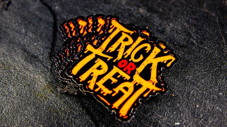 Stack of die cut fluorescent orange stickers with trick or treat design on a table
