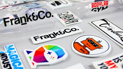 Many custom printed piles of clear stickers on a light grey background and applied to a glass