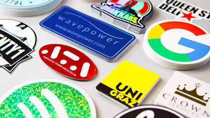 Piles of logo stickers from brands including google on a grey background