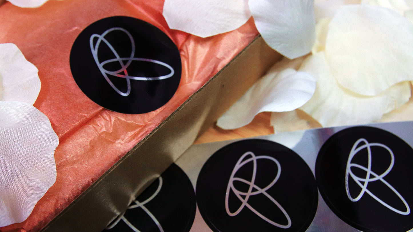 Circle eco-friendly silver logo labels with on applied to secure pink wrapping paper