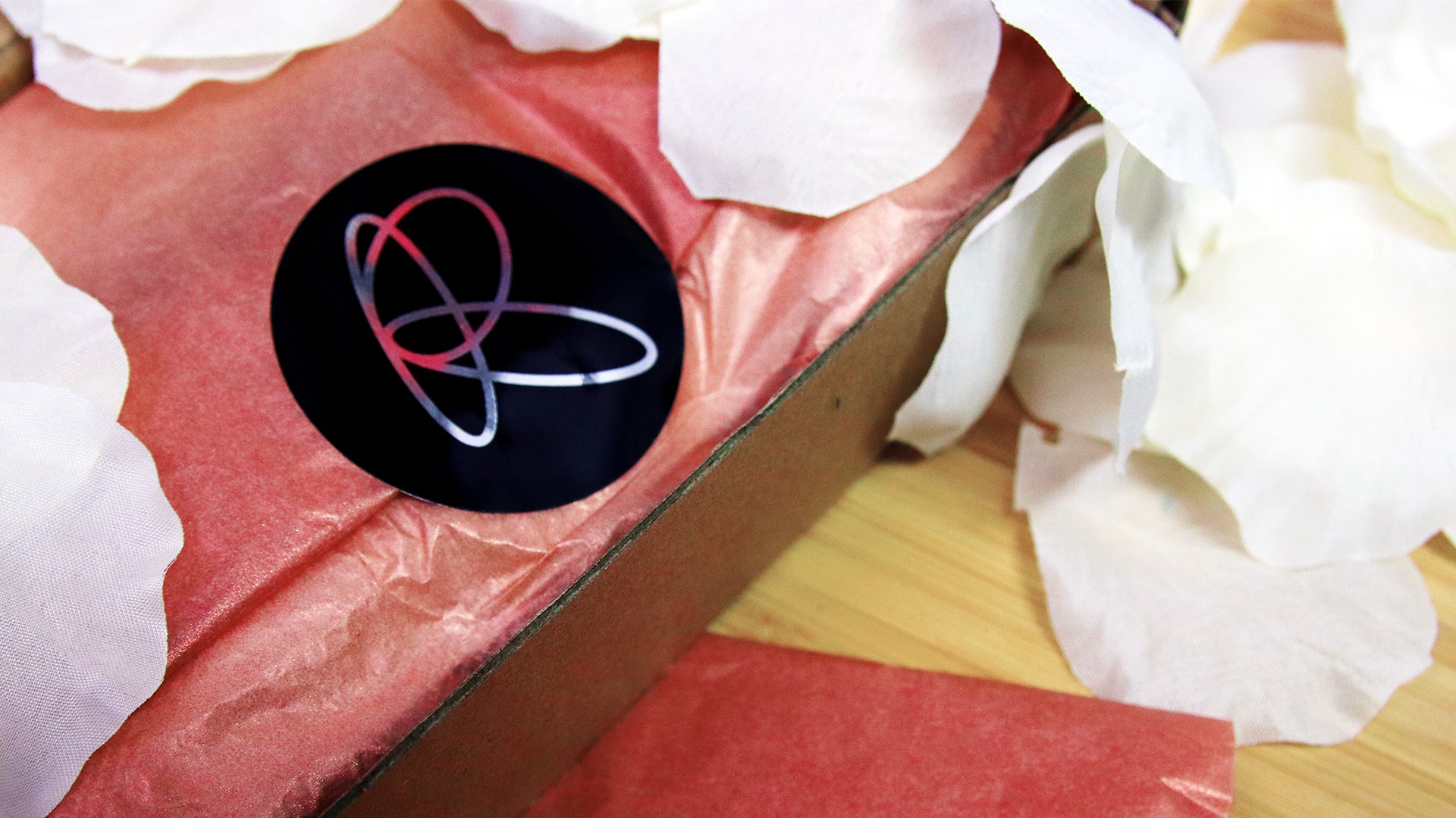 Circle eco-friendly silver logo sticker applied to secure pink wrapping paper