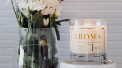 Clear rounded corner label applied to a glass candle jar with a white candle next to white flowers in a vase
