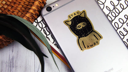 Die cut eco-friendly gold sample with angry cat design applied to a silver phone