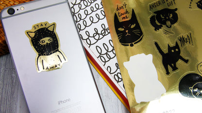 Die cut eco-friendly gold sticker sheets with angry cat design one sticker applied to a silver phone