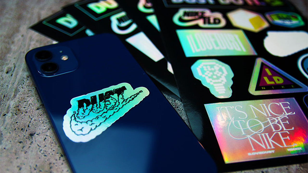 Die cut holographic labels with one design peeled and applied to a black phone
