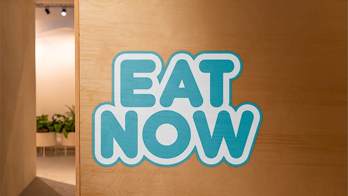 Die cut wall sticker sample with eat now design applied to an office wall