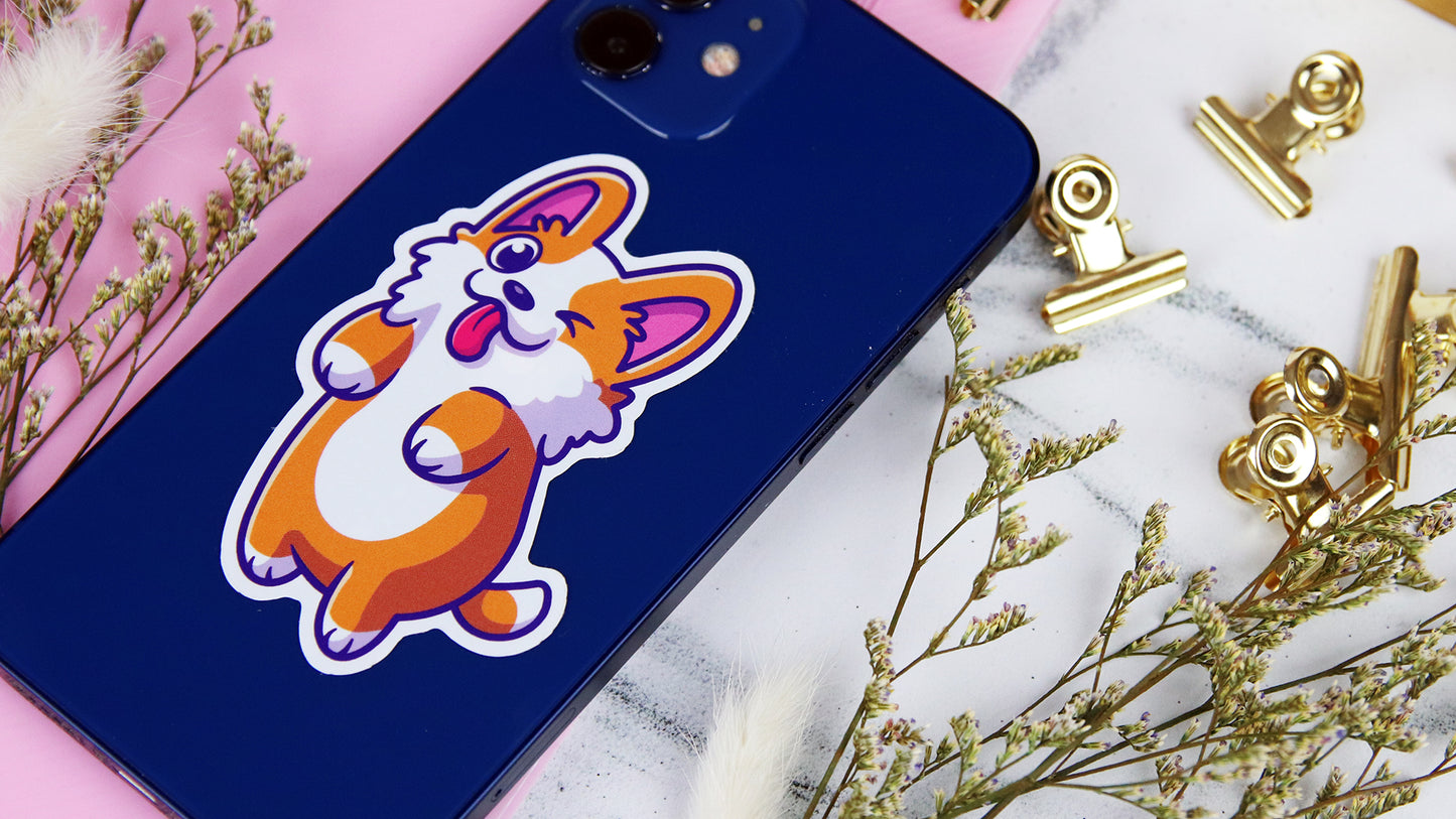 Die cut white vinyl sticker with corgi design applied to an iPhone on a table