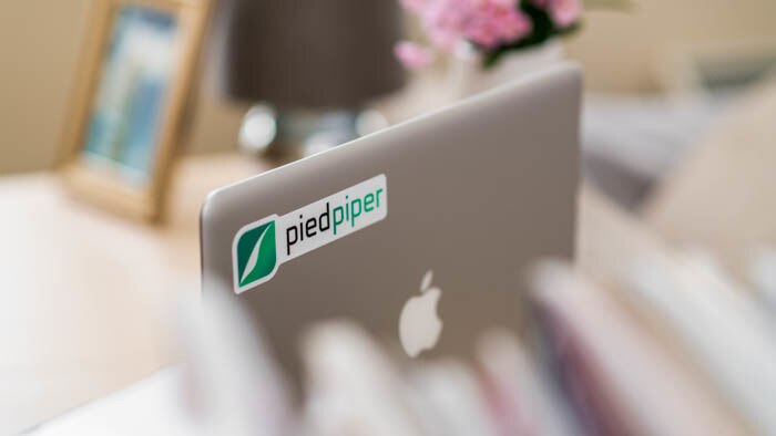Die cut white vinyl sticker with pied piper logo applied to a silver laptop