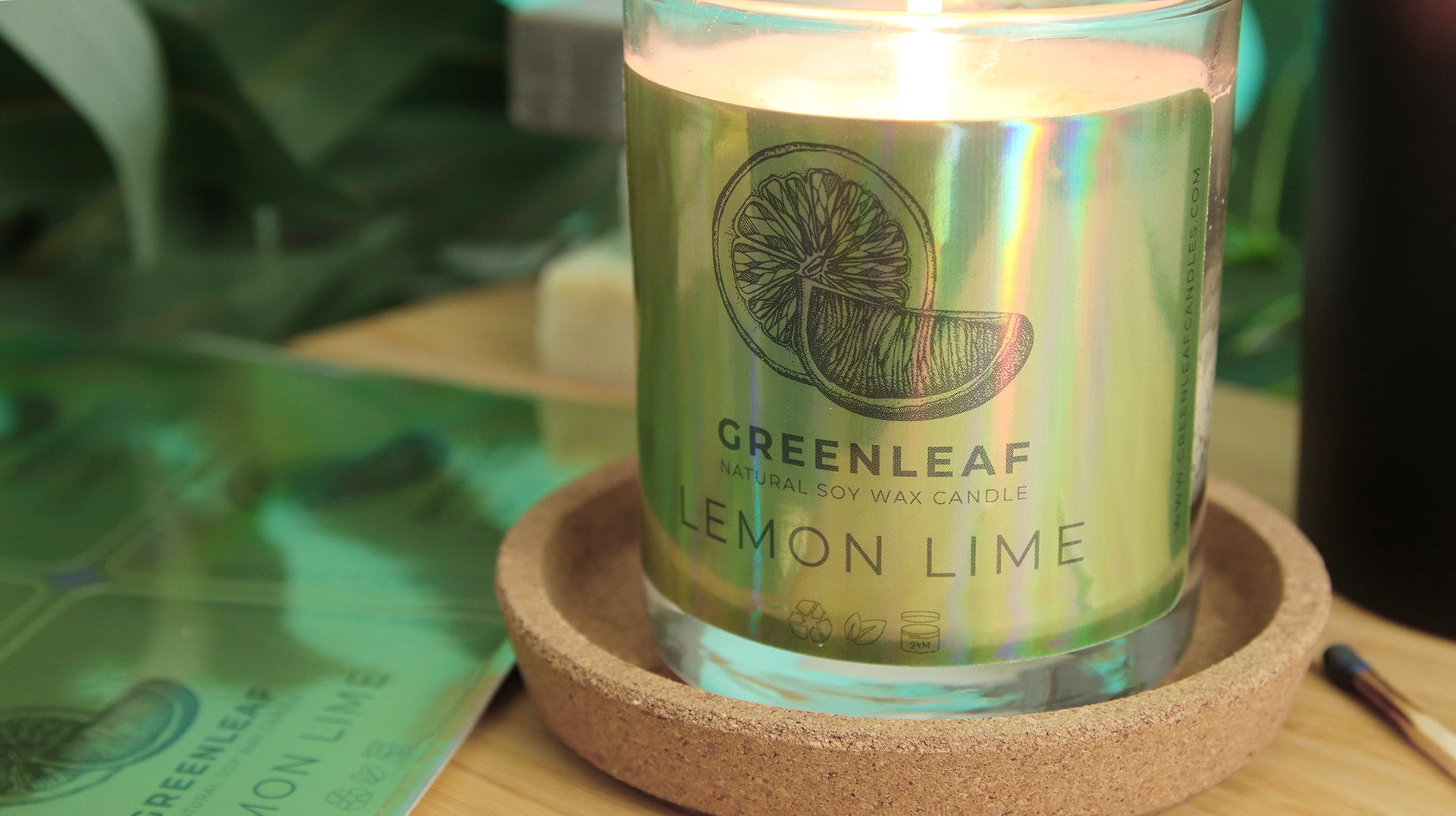Eco-friendly holographic label with green leaf label applied to a candle next to sticker sheets