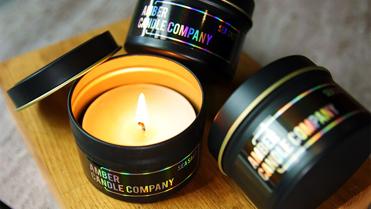 Eco-friendly holographic labels applied to black candle tins