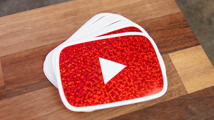 Glitter stickers with rounded corners and the YouTube logo on a wooden board
