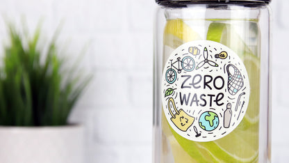 Round sticker with zero waste design applied to a glass water bottle filled with lemons and limes