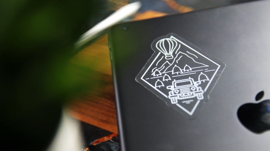 Transparent die cut sticker with adventure logo applied to silver laptop