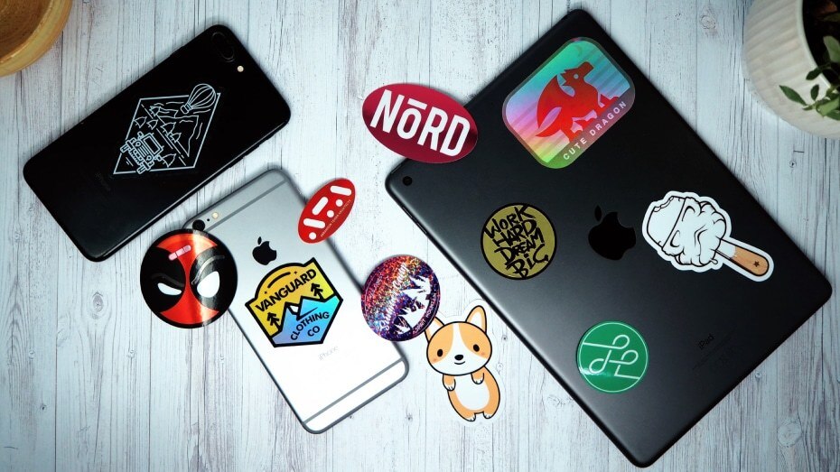 Various die cut stickers stuck to a phone on a white wooden table