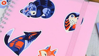 White vinyl die cut stickers with cute animals some peeled and applied to a pink note book