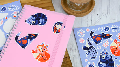 White vinyl die cut labels with cute animals some peeled and applied to a pink note book