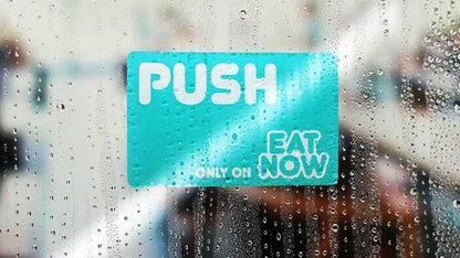 Window cling with eat now logo applied to a glass window